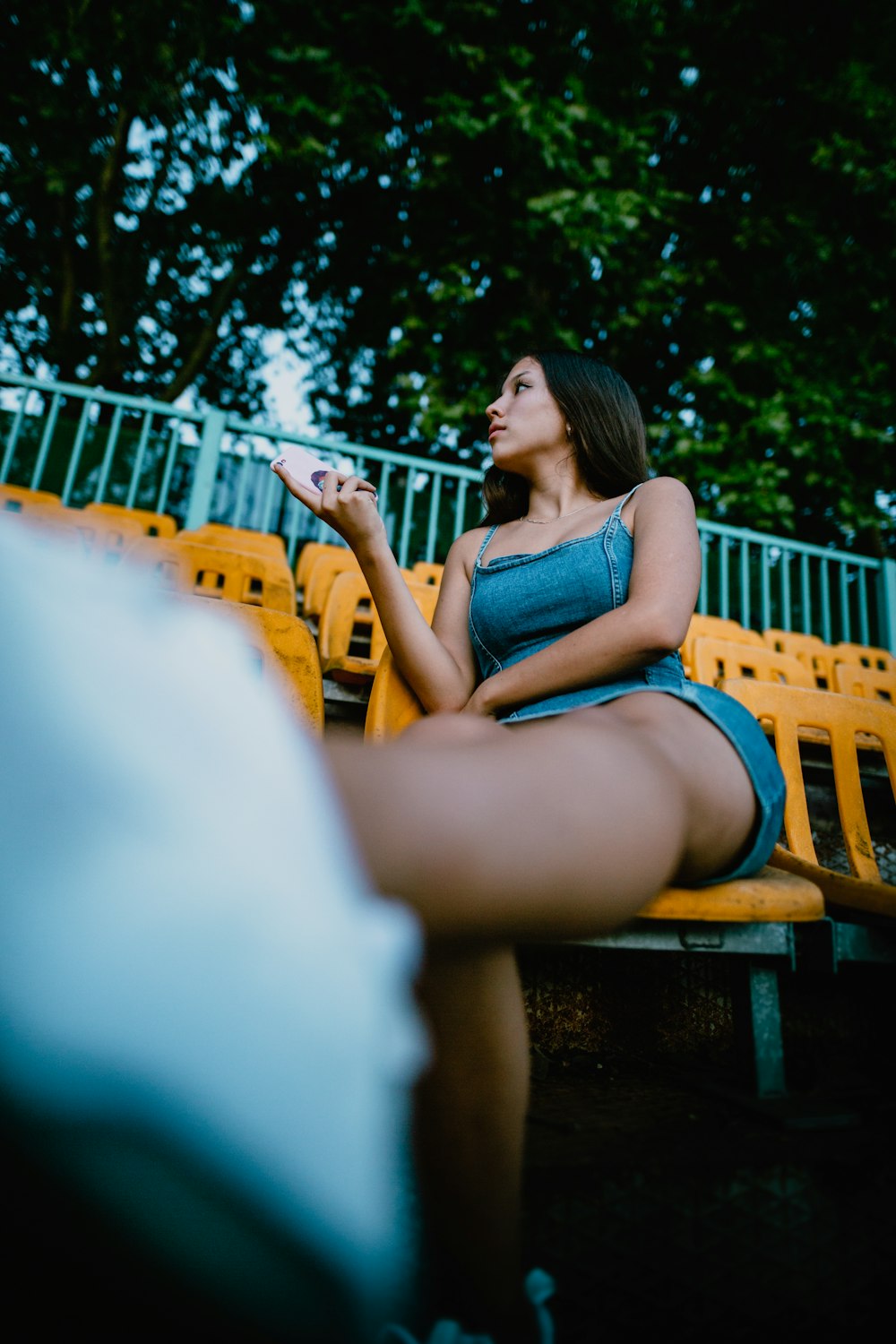 woman in blue tank top sitting on brown wooden bench during daytime