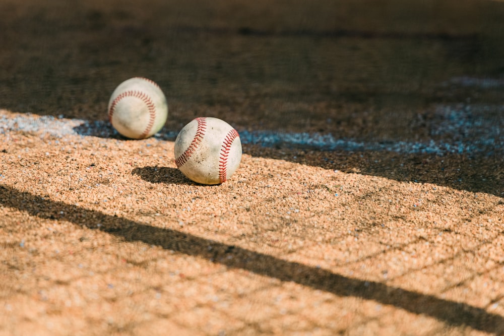 white and red baseball on brown sand