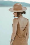 woman in brown spaghetti strap dress wearing beige hat