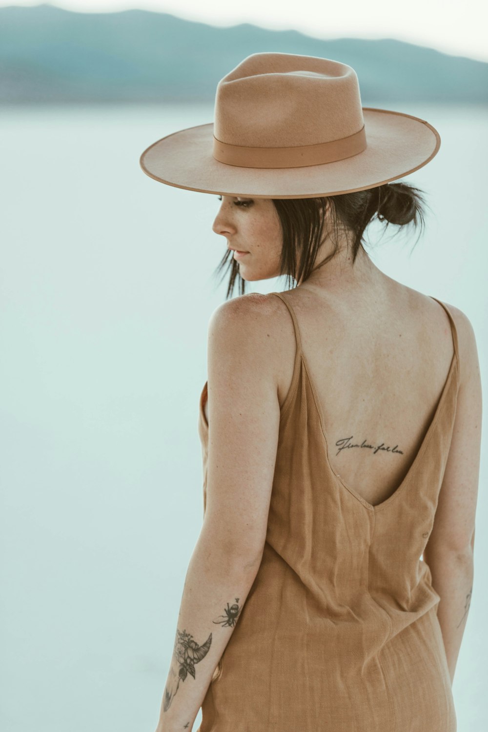 Mujer con vestido marrón de tirantes finos con sombrero beige