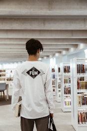 man in white long sleeve shirt standing in front of white wooden shelf