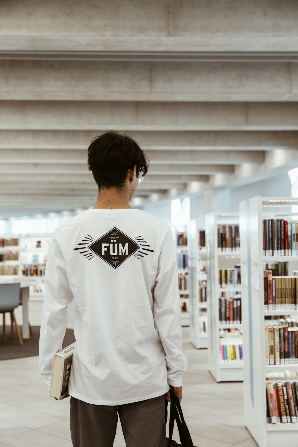 man in white long sleeve shirt standing in front of white wooden shelf