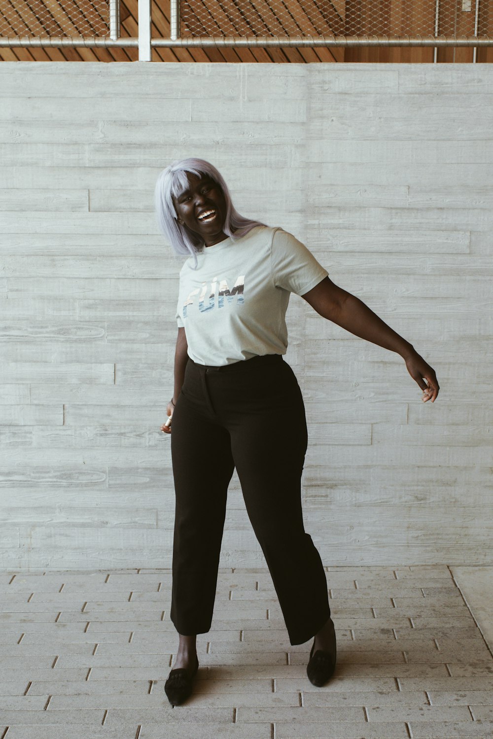 woman in white t-shirt and black pants standing on brown wooden floor