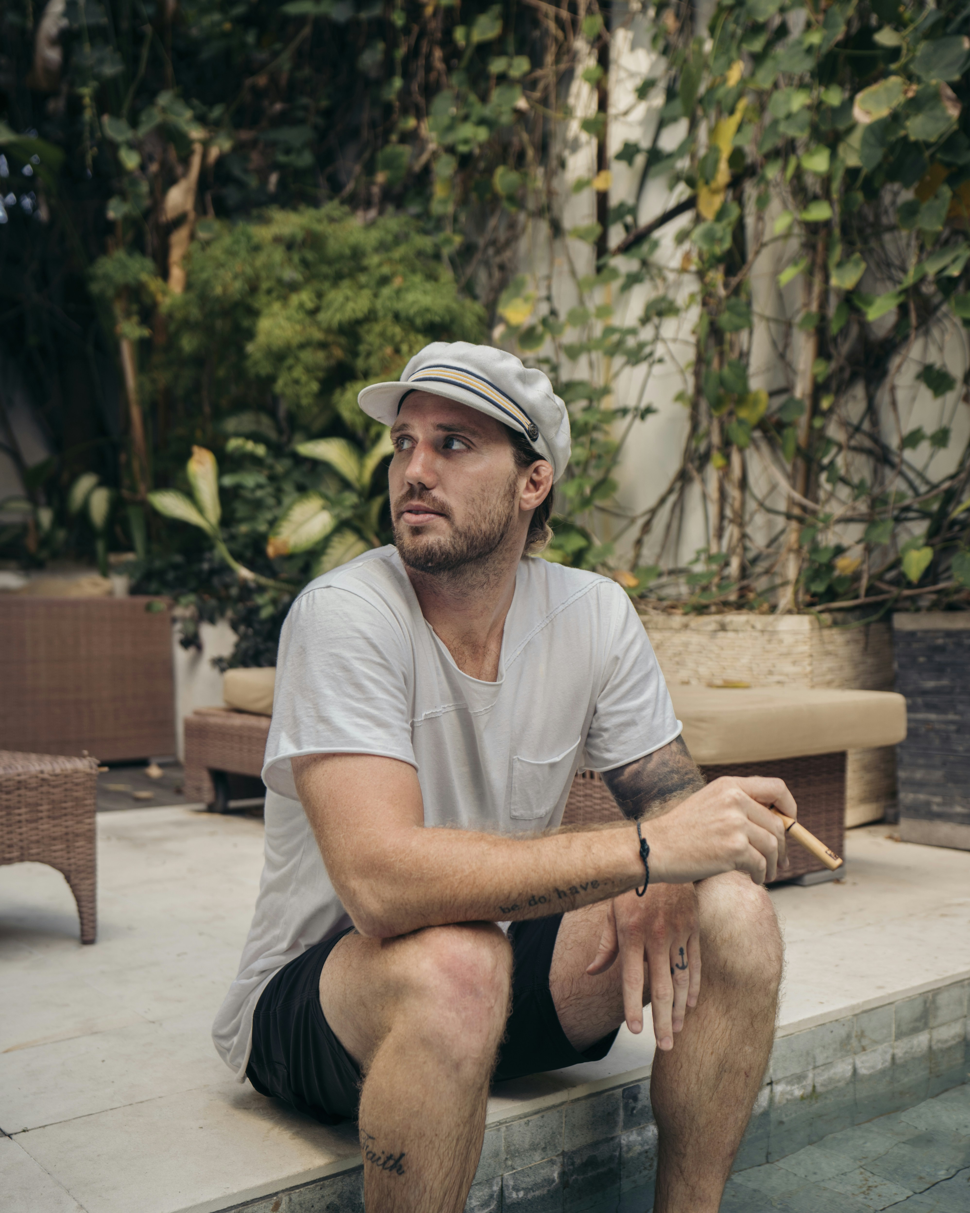 man in white crew neck t-shirt sitting on brown wooden bench