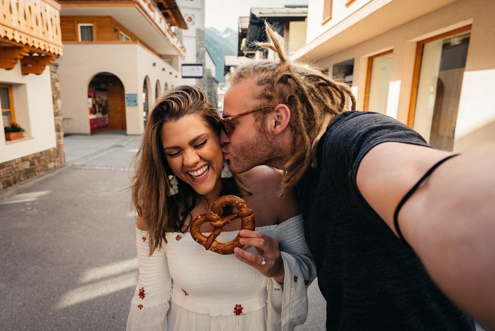 man and woman smiling while holding brown heart shaped balloons