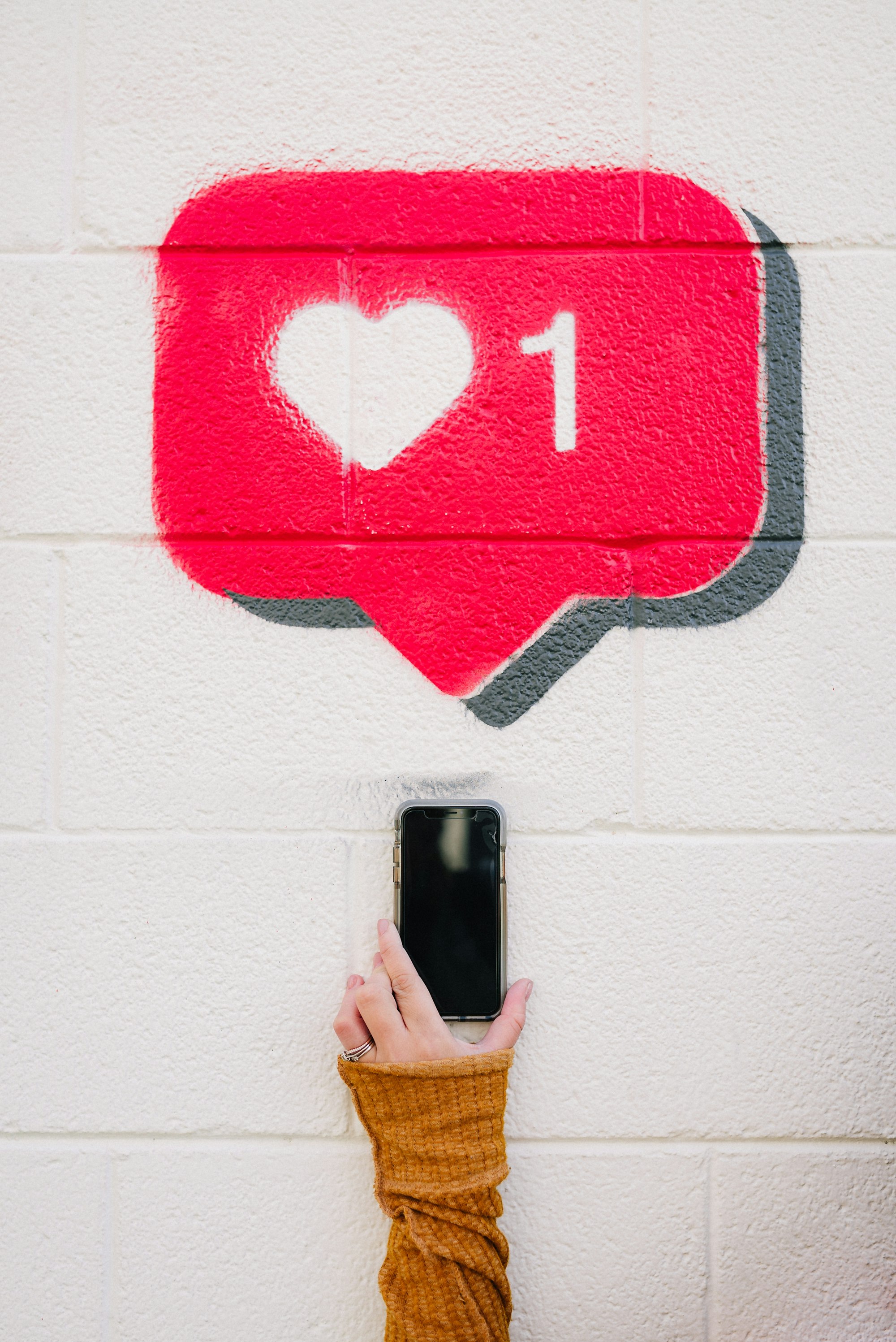 Wall painting showing an Instagram like as a hand holds an iPhone towards the notification symbol.