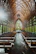 A couple exchanging vows in a cozy chapel surrounded by wooden pews and soft light.