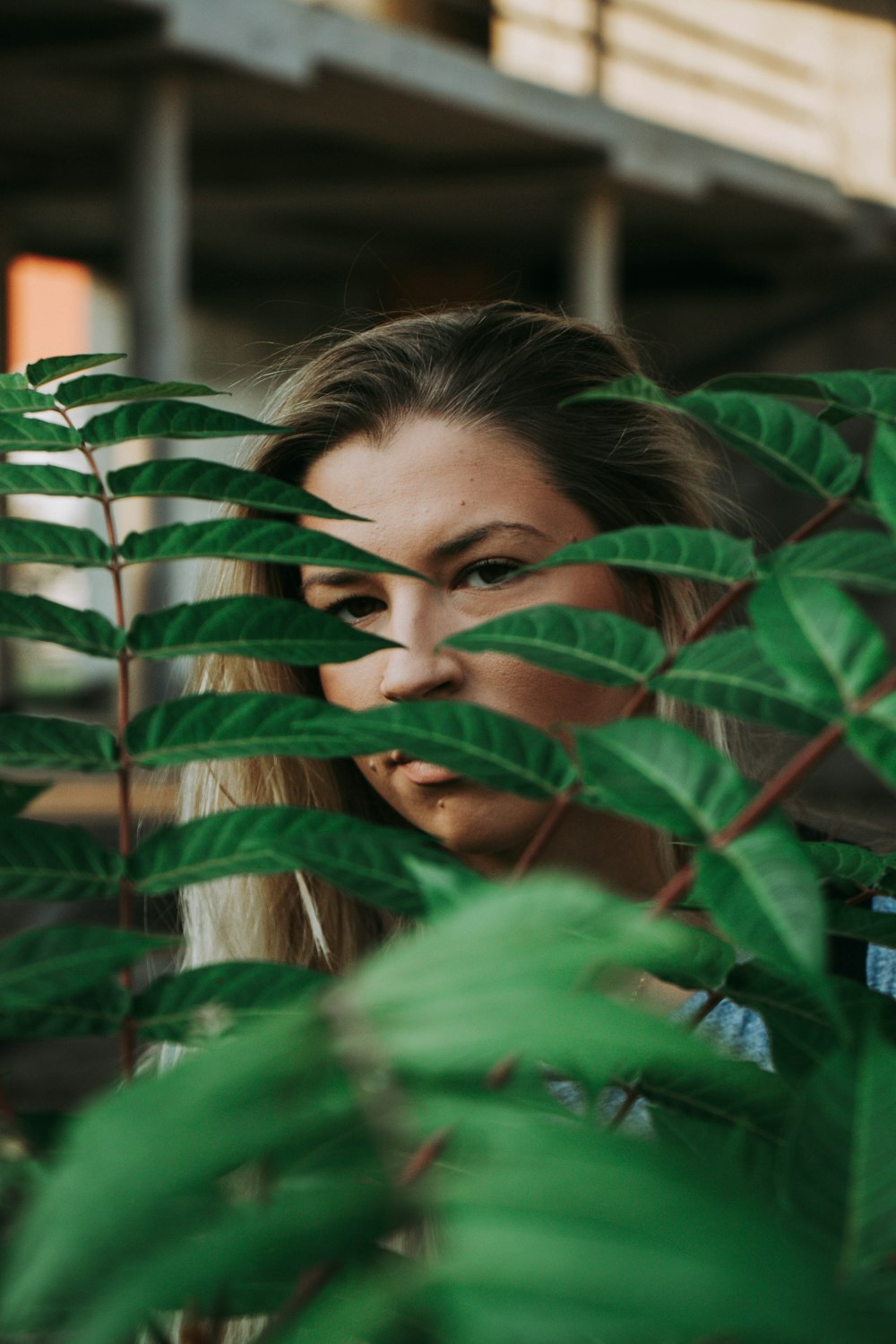 girl covering her face with green leaves