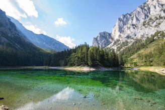 The sparkling waters of one of the 7 Rila Lakes reflecting surrounding pine trees and rocky peaks.