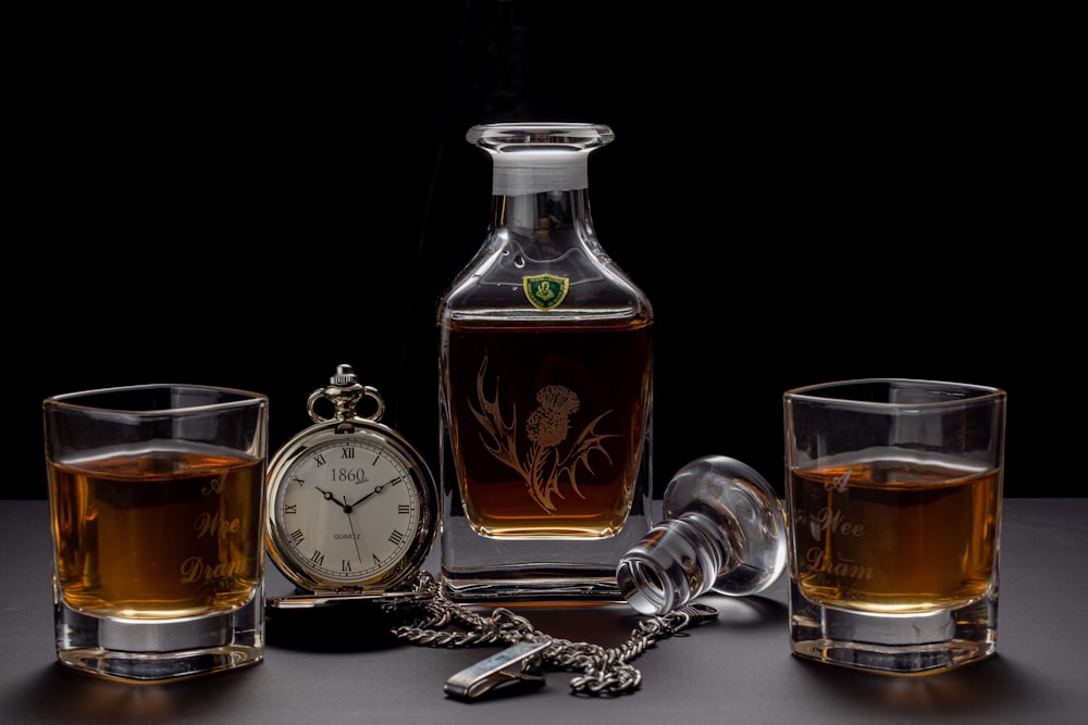 silver pocket watch beside glass bottle