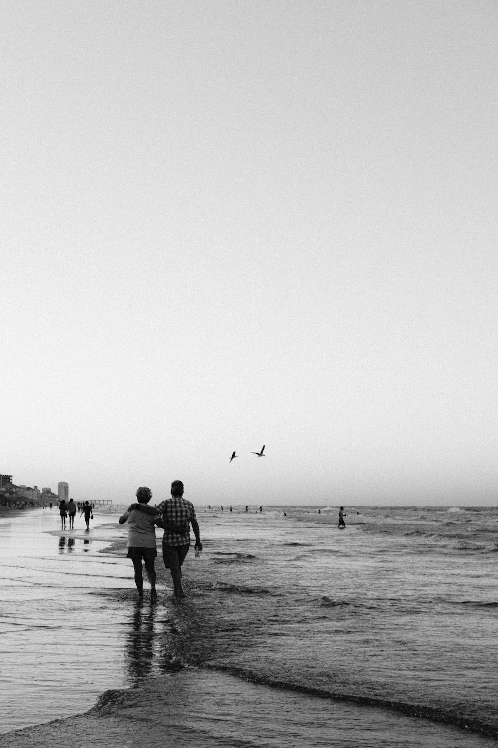 grayscale photo of people walking on beach