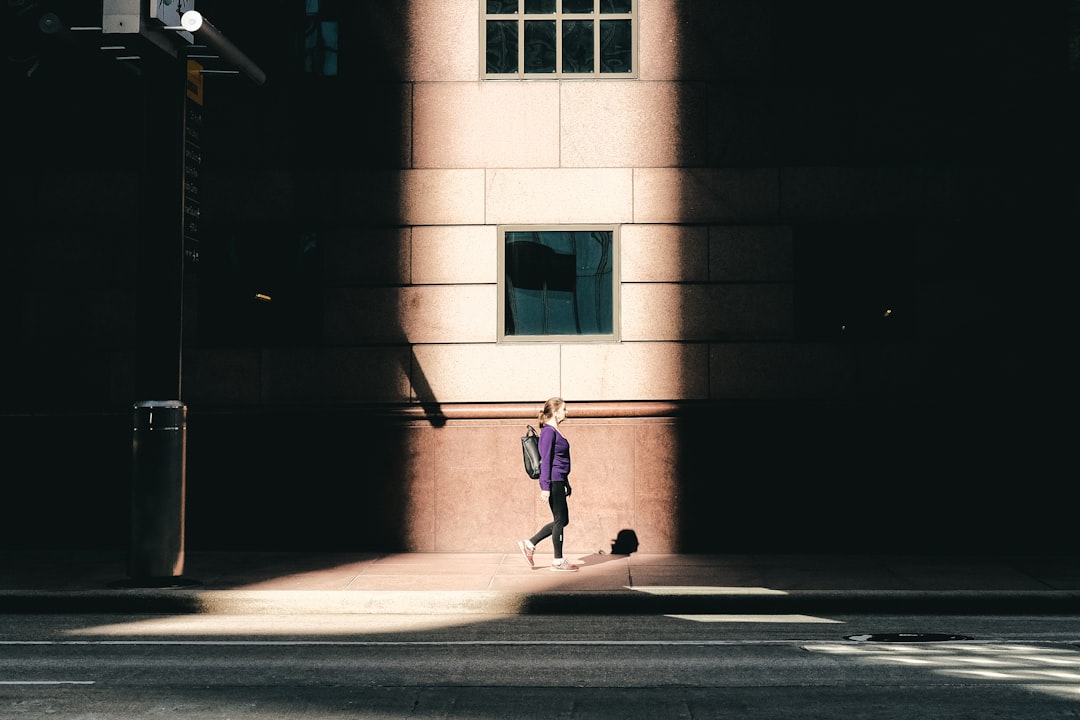 girl in pink jacket and pants walking on sidewalk during daytime