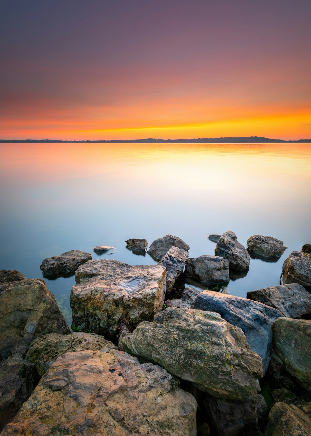 gray and brown rocks near body of water during sunset