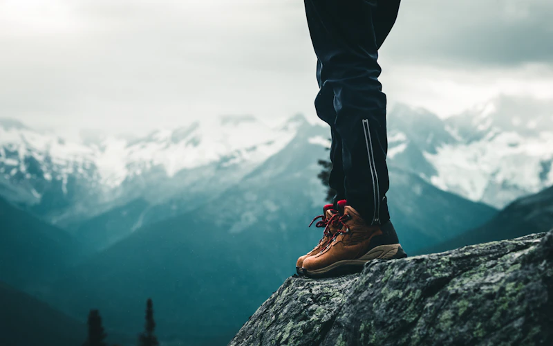 pendaki memakai sepatu gunung mid-cut di atas batu