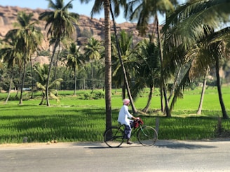 man in white shirt riding bicycle on road during daytime