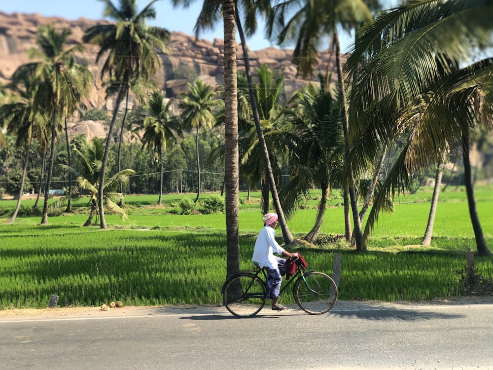 hombre en camisa blanca montando en bicicleta en la carretera durante el día