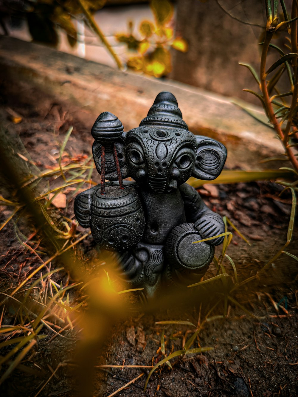 black frog figurine on brown dried leaves