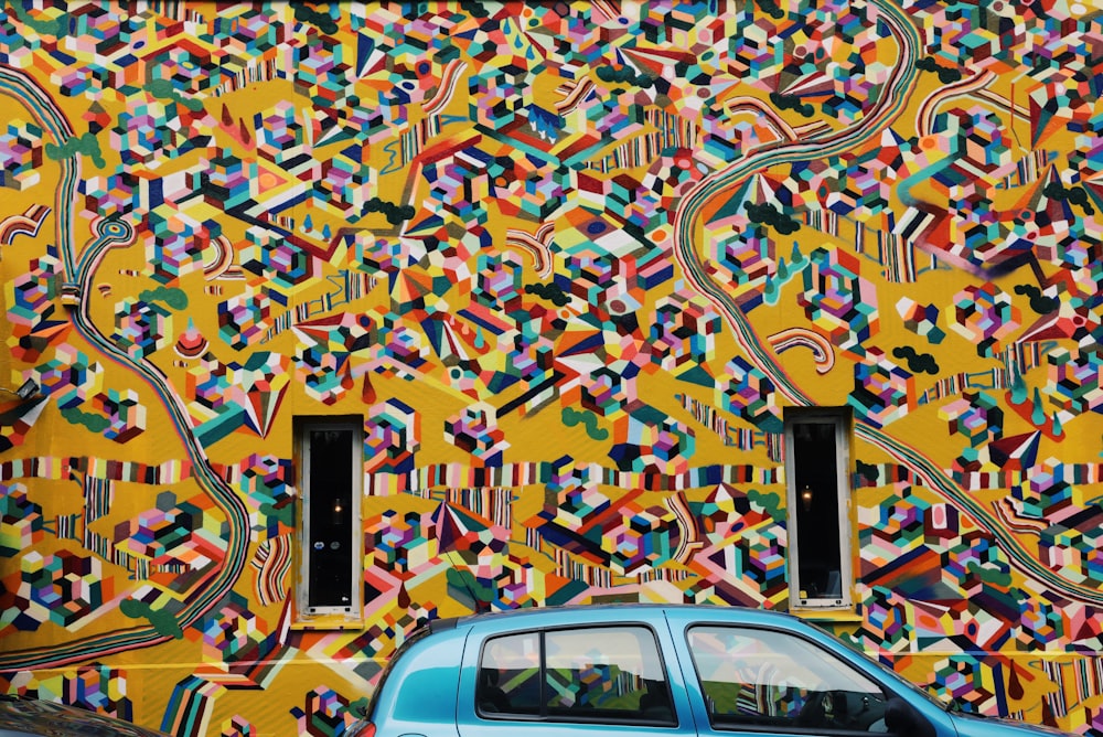 a blue car parked in front of a colorful building