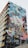 A building features a large, colorful mural depicting a woman in a ballet pose, seemingly leaping into the air with the city skyline in the background. The mural consists of vivid blocks of color and various artistic patterns.