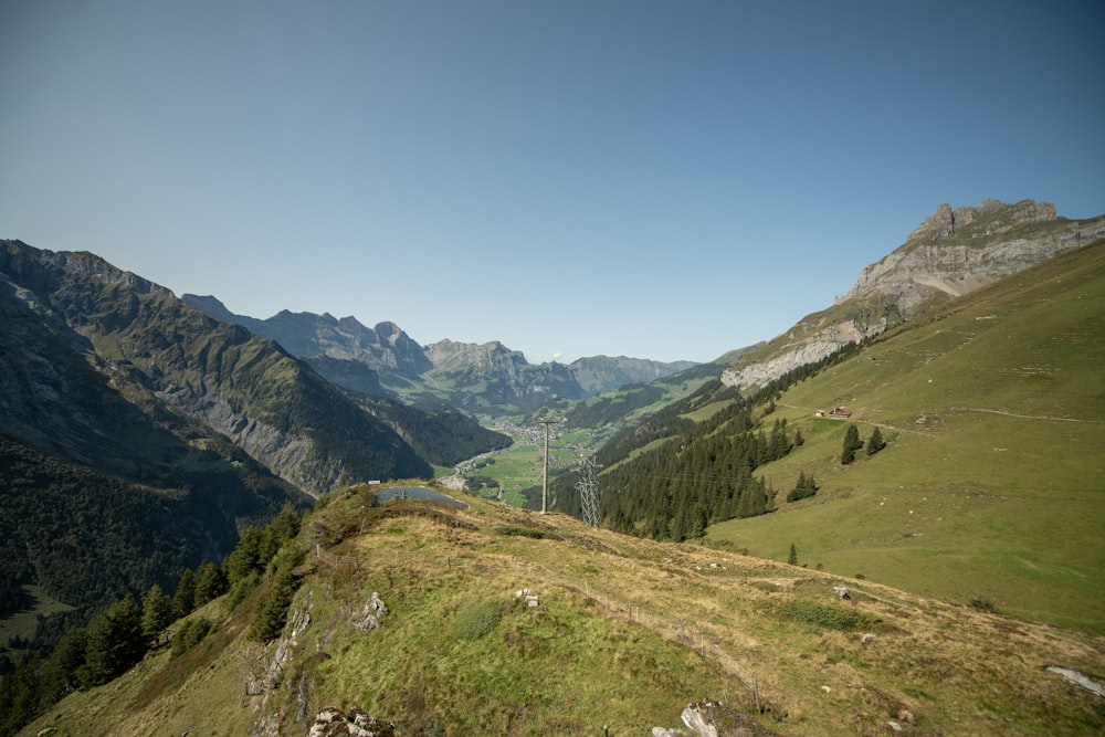 green grass field and mountains under blue sky during daytime