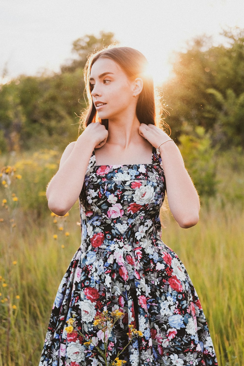 woman in black red and white floral spaghetti strap dress standing on green grass field during