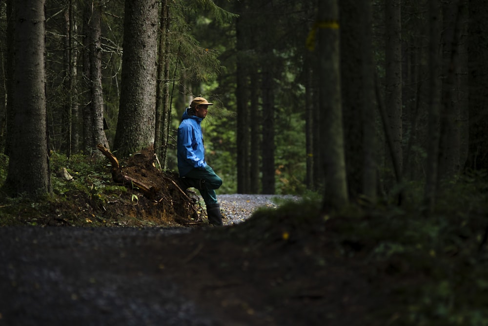 man in blue jacket and blue denim jeans standing on forest during daytime