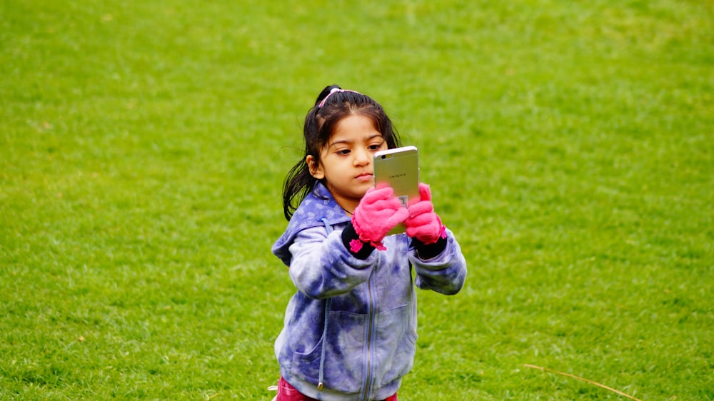 girl in blue jacket holding white smartphone