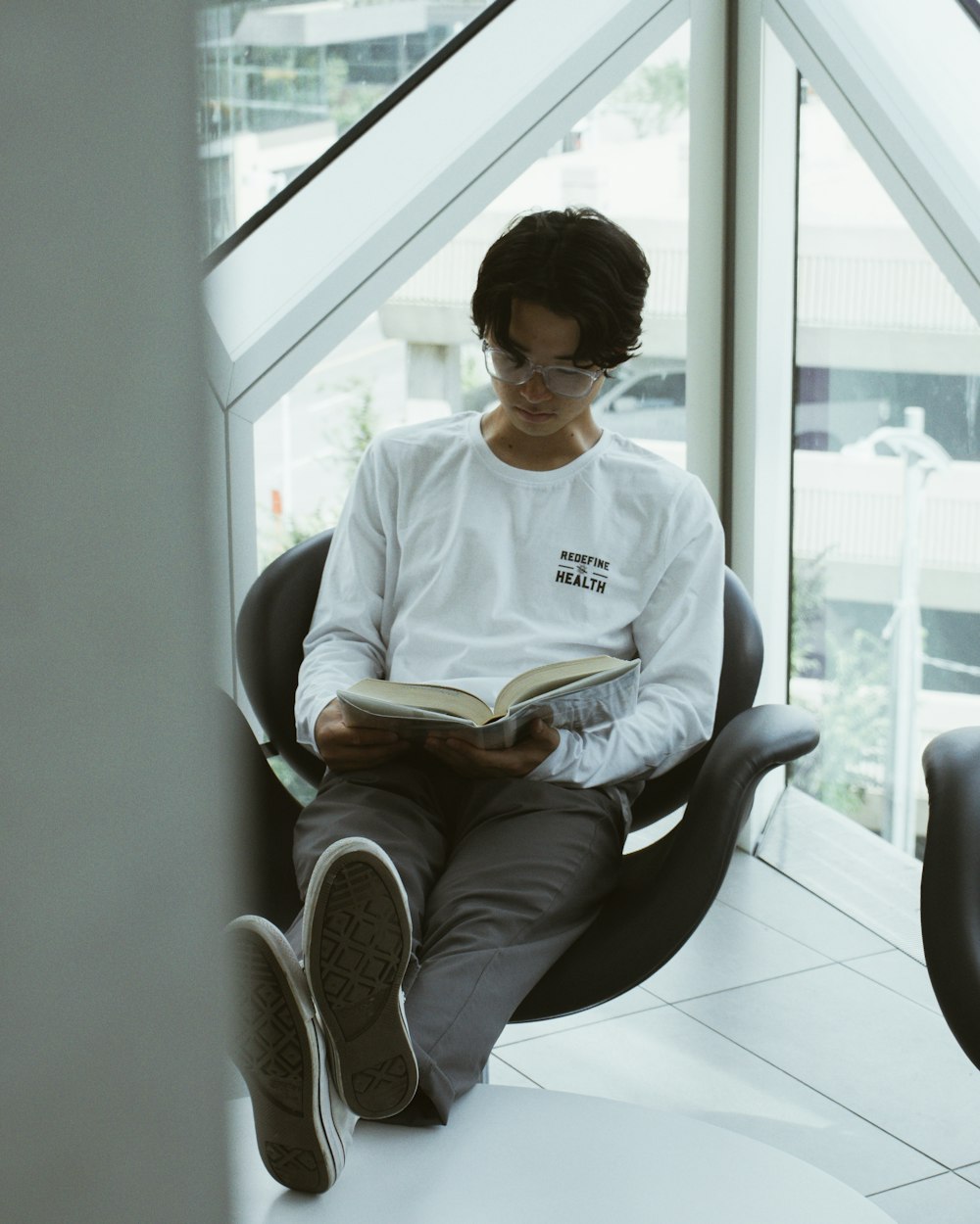 man in white crew neck t-shirt sitting on black armchair