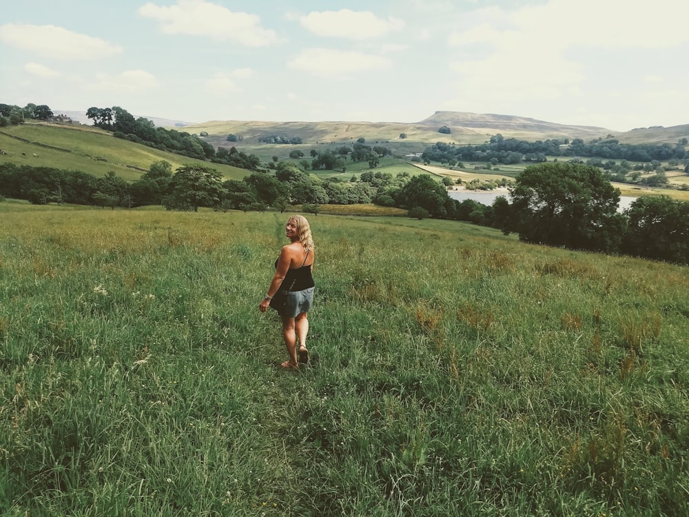 woman in black tank top and black shorts standing on green grass field during daytime