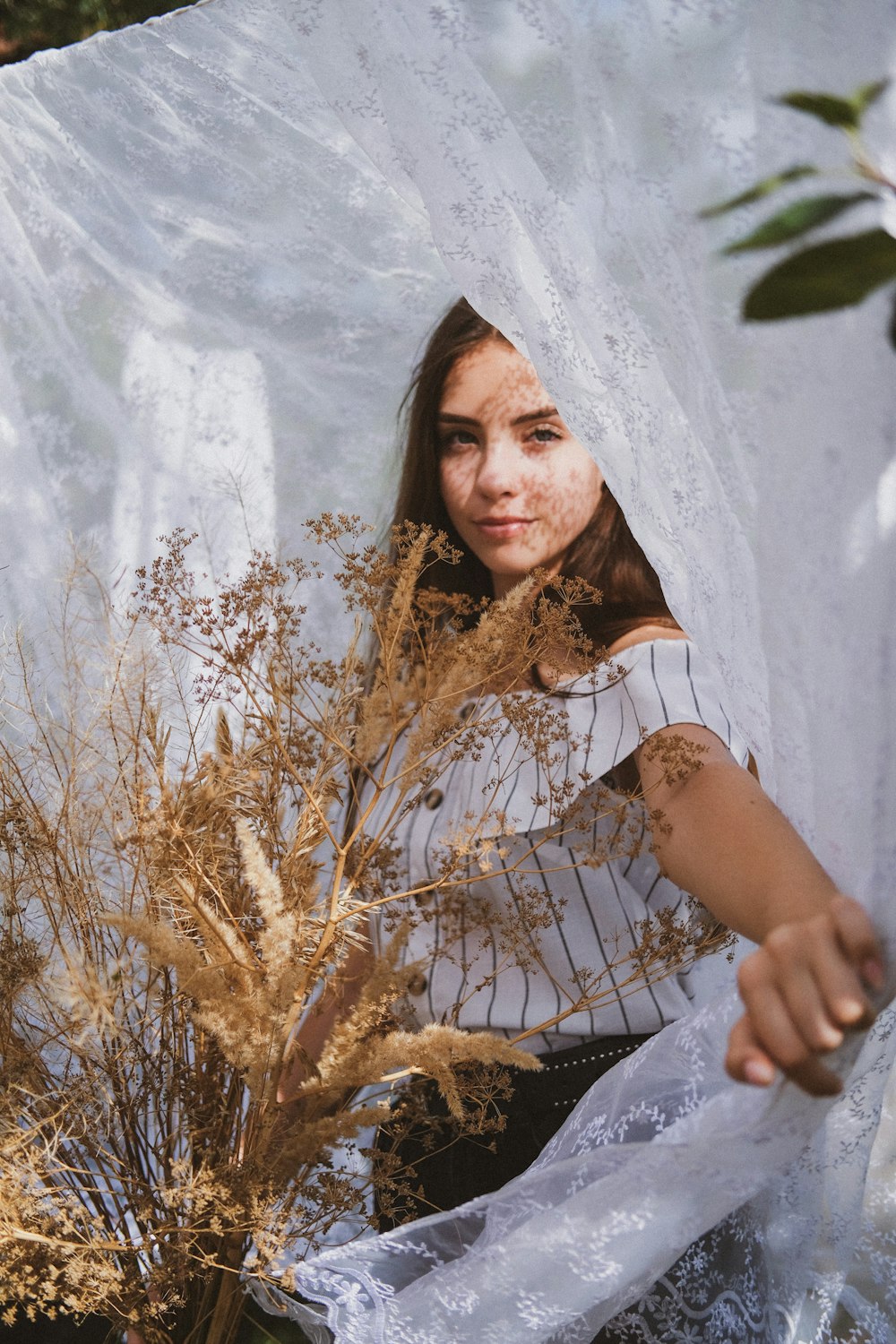 woman in white and black floral dress standing beside brown grass during daytime