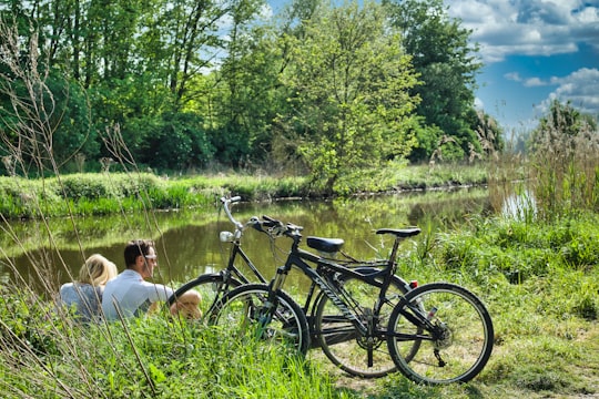 man and woman sitting on grass field beside black bicycle during daytime in Bourgoyen-Ossemeersen Belgium