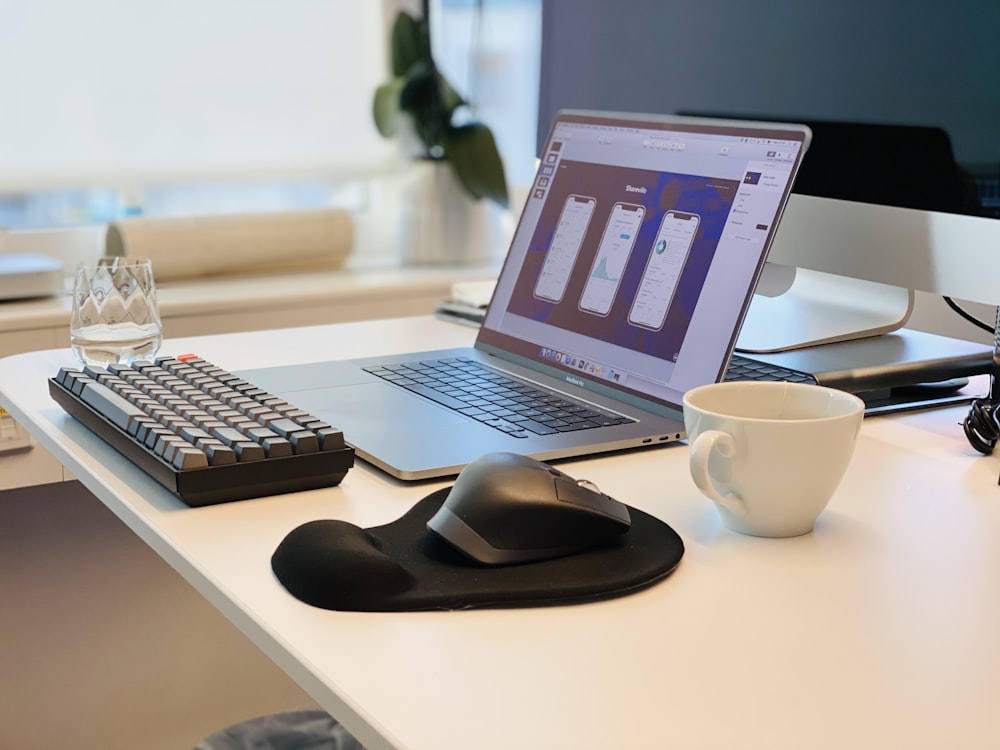 macbook pro ao lado do mouse preto do computador e teclado preto do computador na mesa branca
