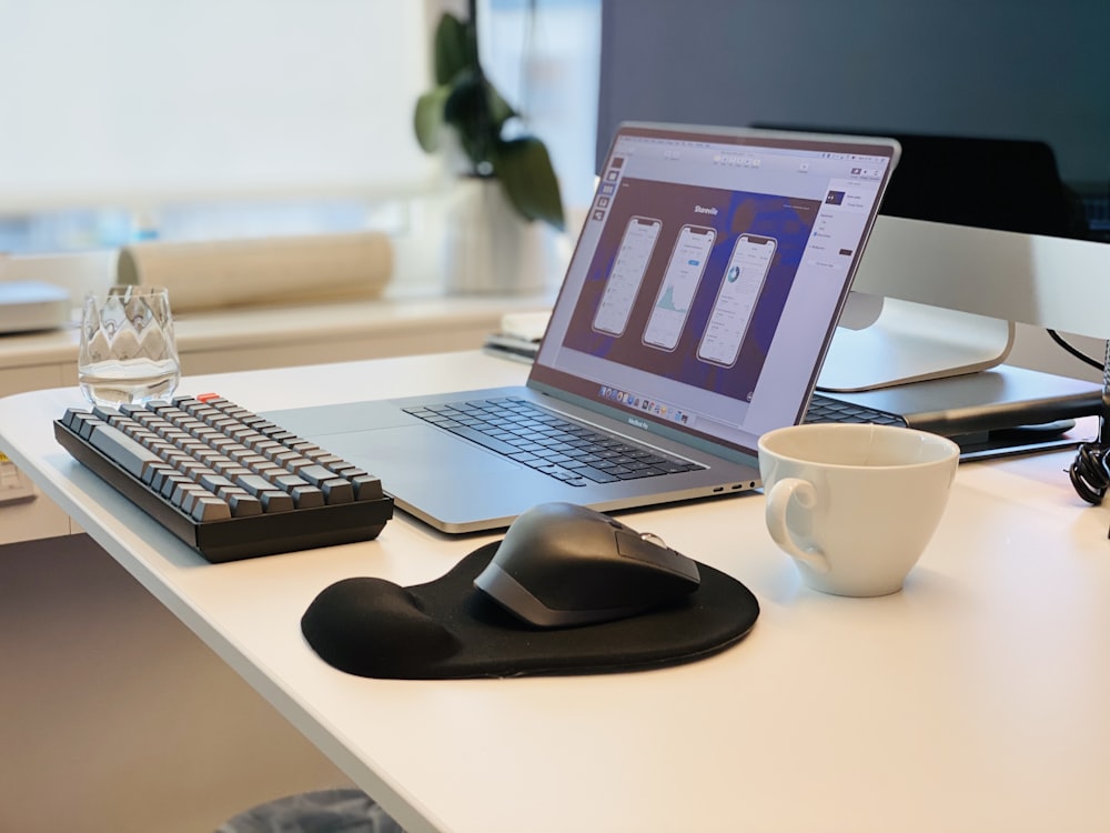 macbook pro beside black computer mouse and black computer keyboard on white table