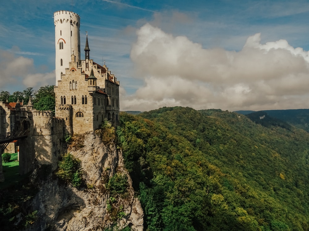 gray concrete castle on top of green mountain under cloudy sky during daytime