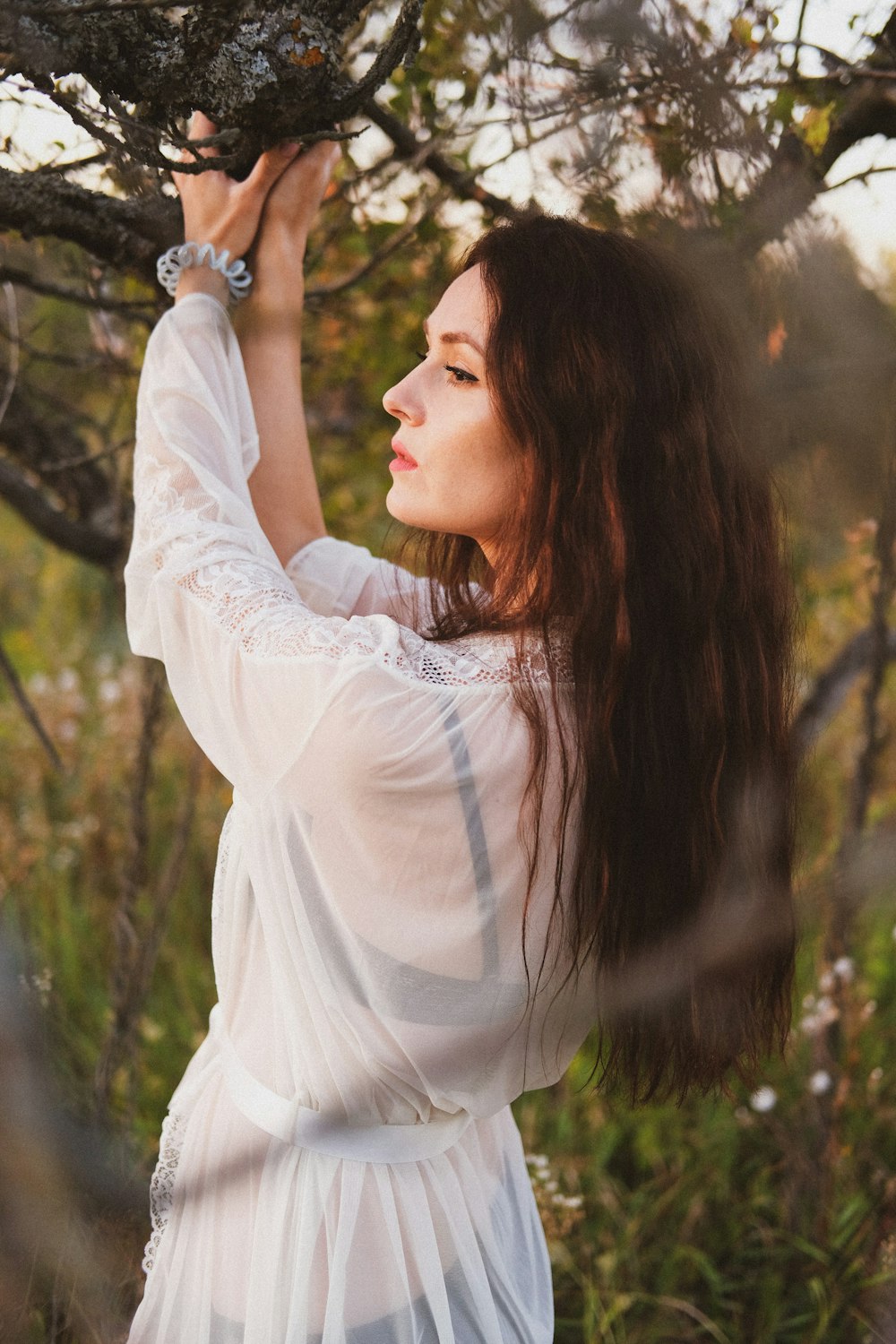 woman in white long sleeve shirt holding her hair
