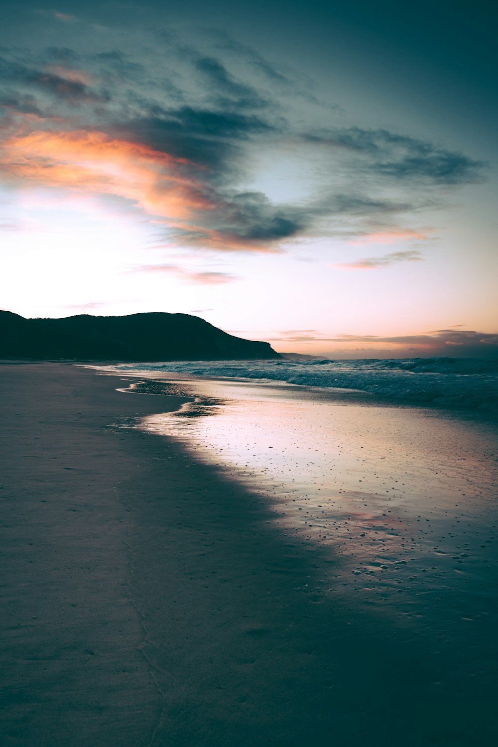 body of water near mountain during sunset