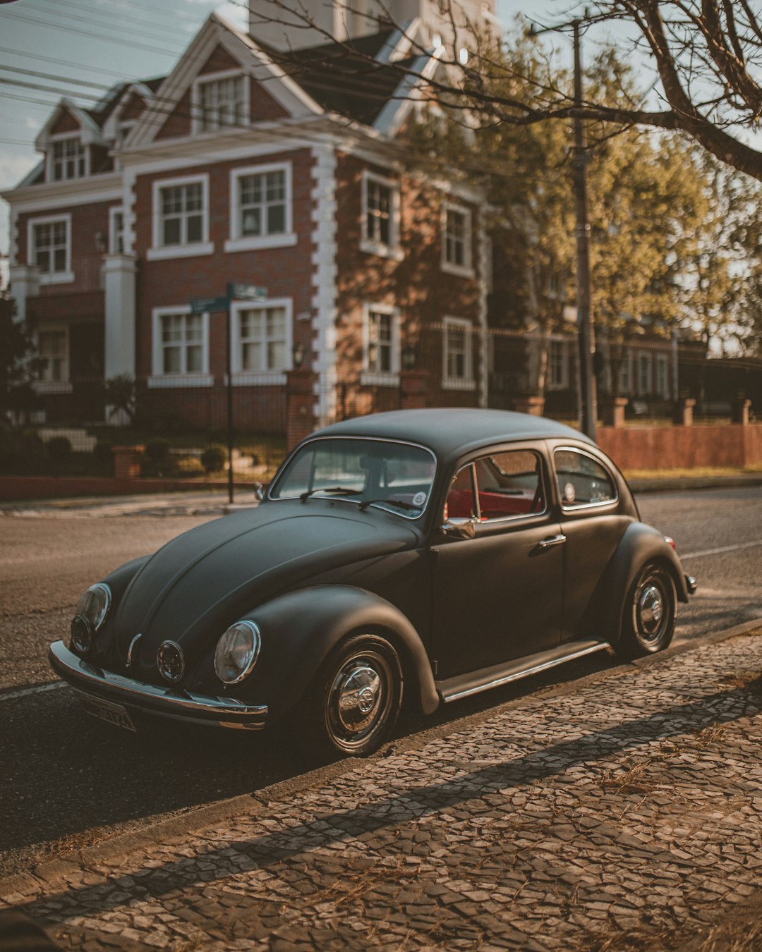 black volkswagen beetle parked on side of the road during daytime