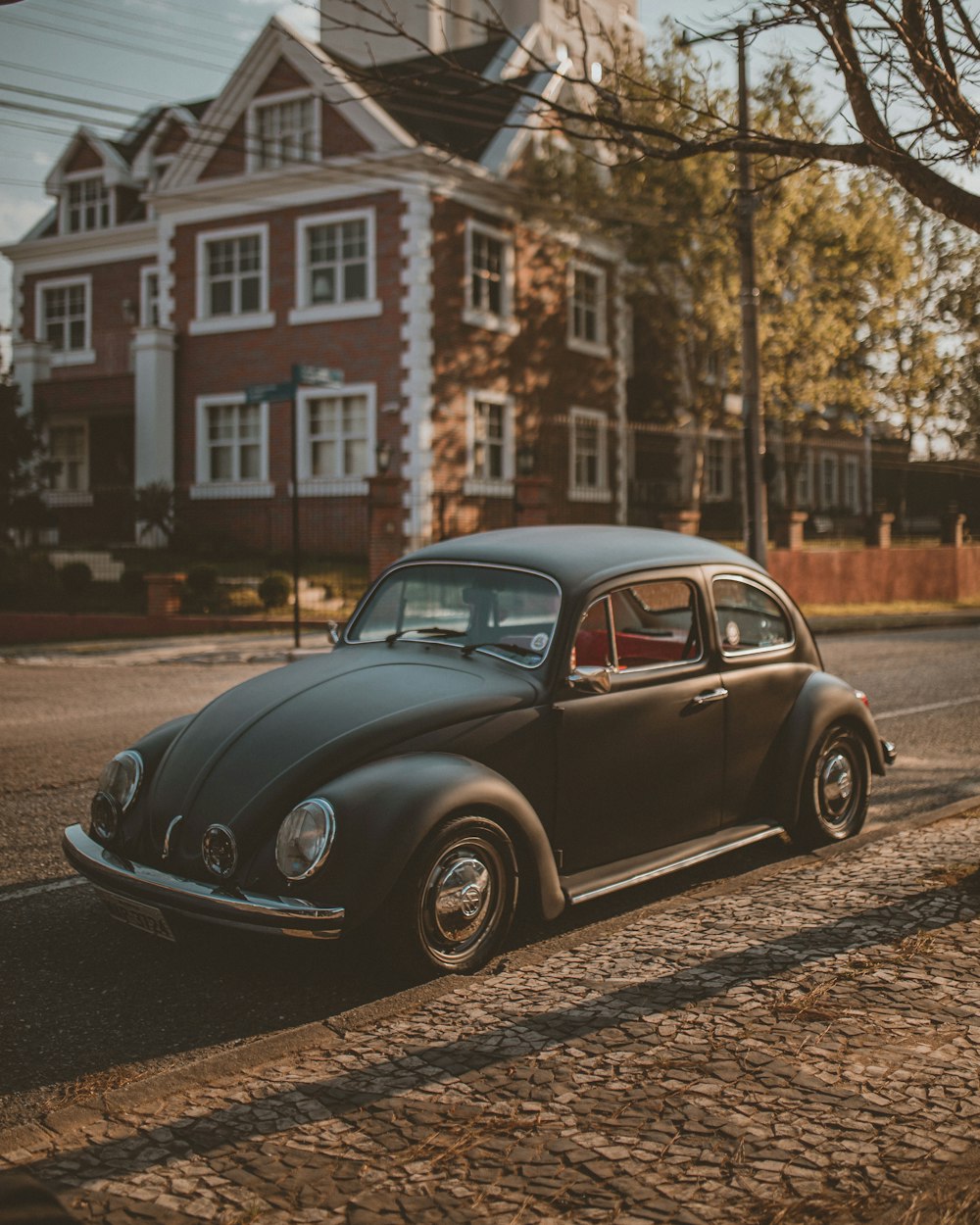 black volkswagen beetle parked on side of the road during daytime