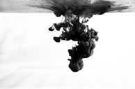 Subtle waves of ink spreading gently across a neutral dark surface, hinting at thoughtful motion.