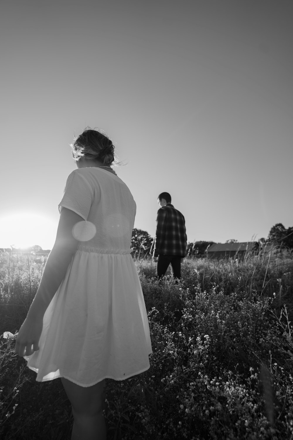 grayscale photo of couple walking on grass field