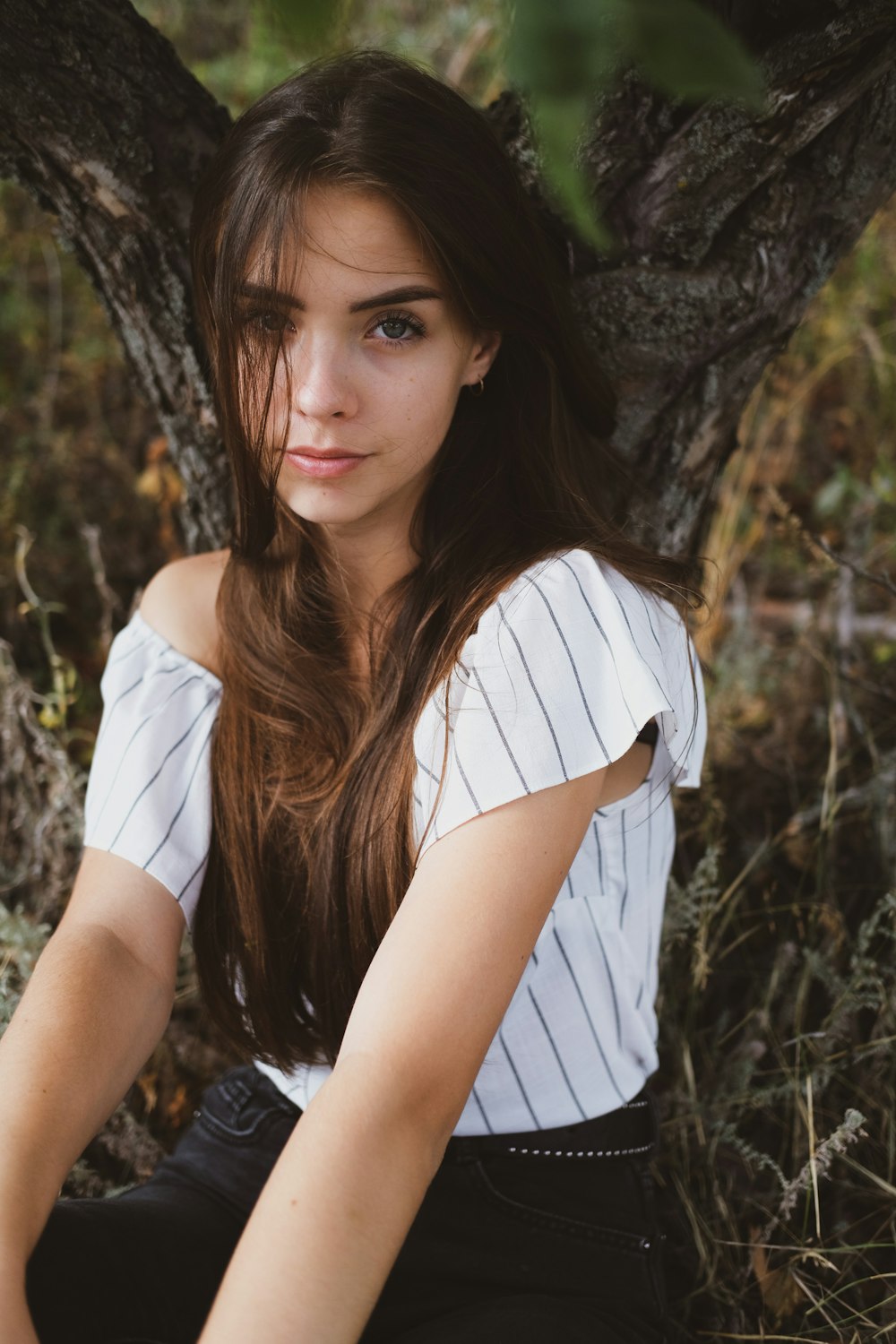 woman in white and black stripe shirt sitting on brown rock