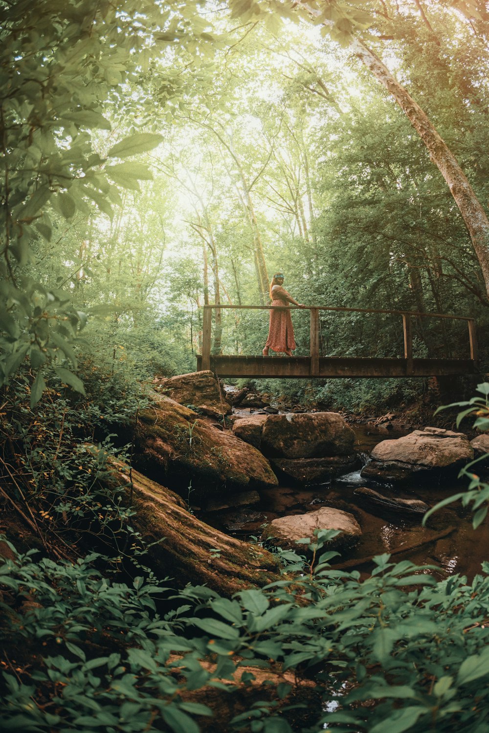 woman in brown dress walking on brown wooden bridge