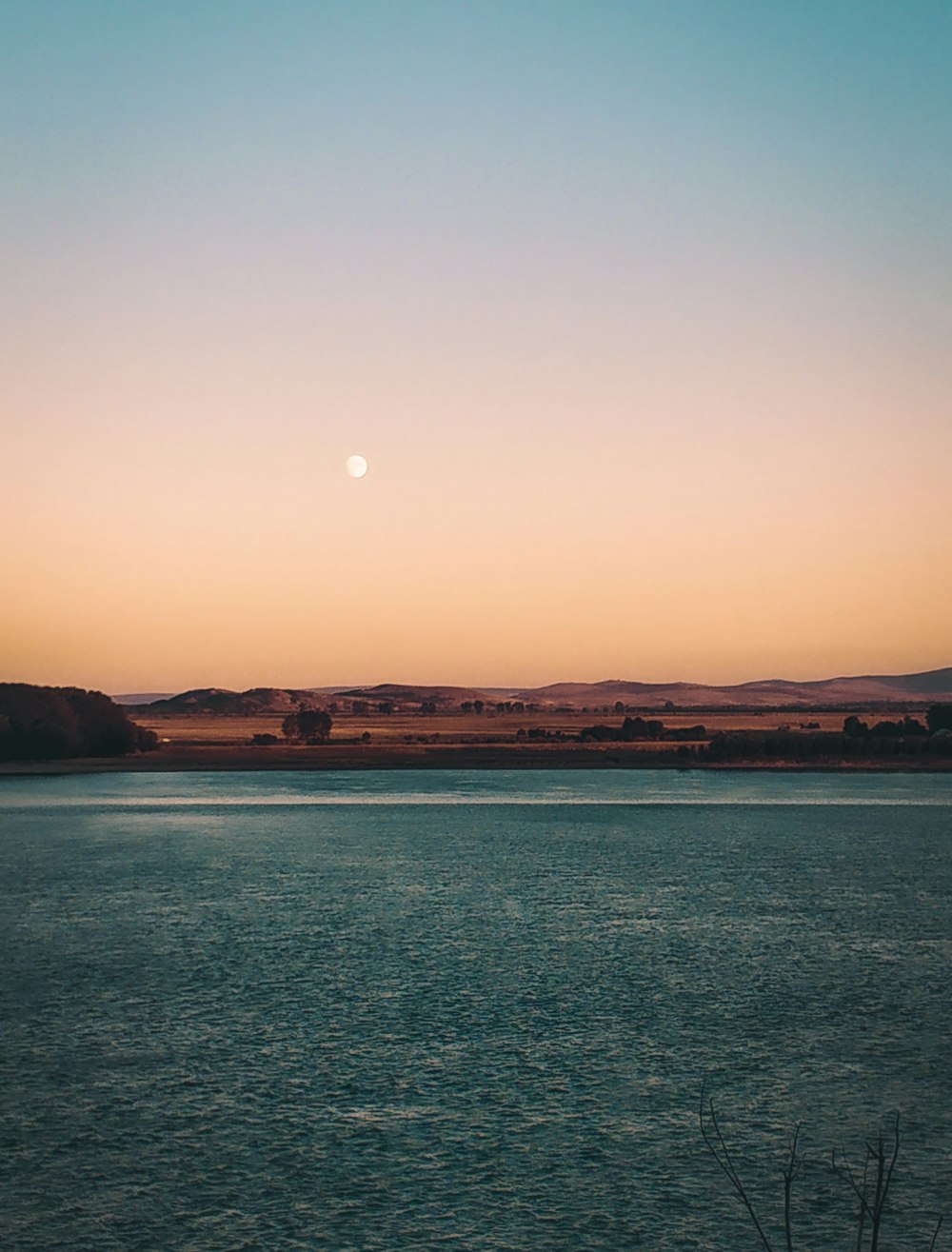 body of water near mountain during sunset