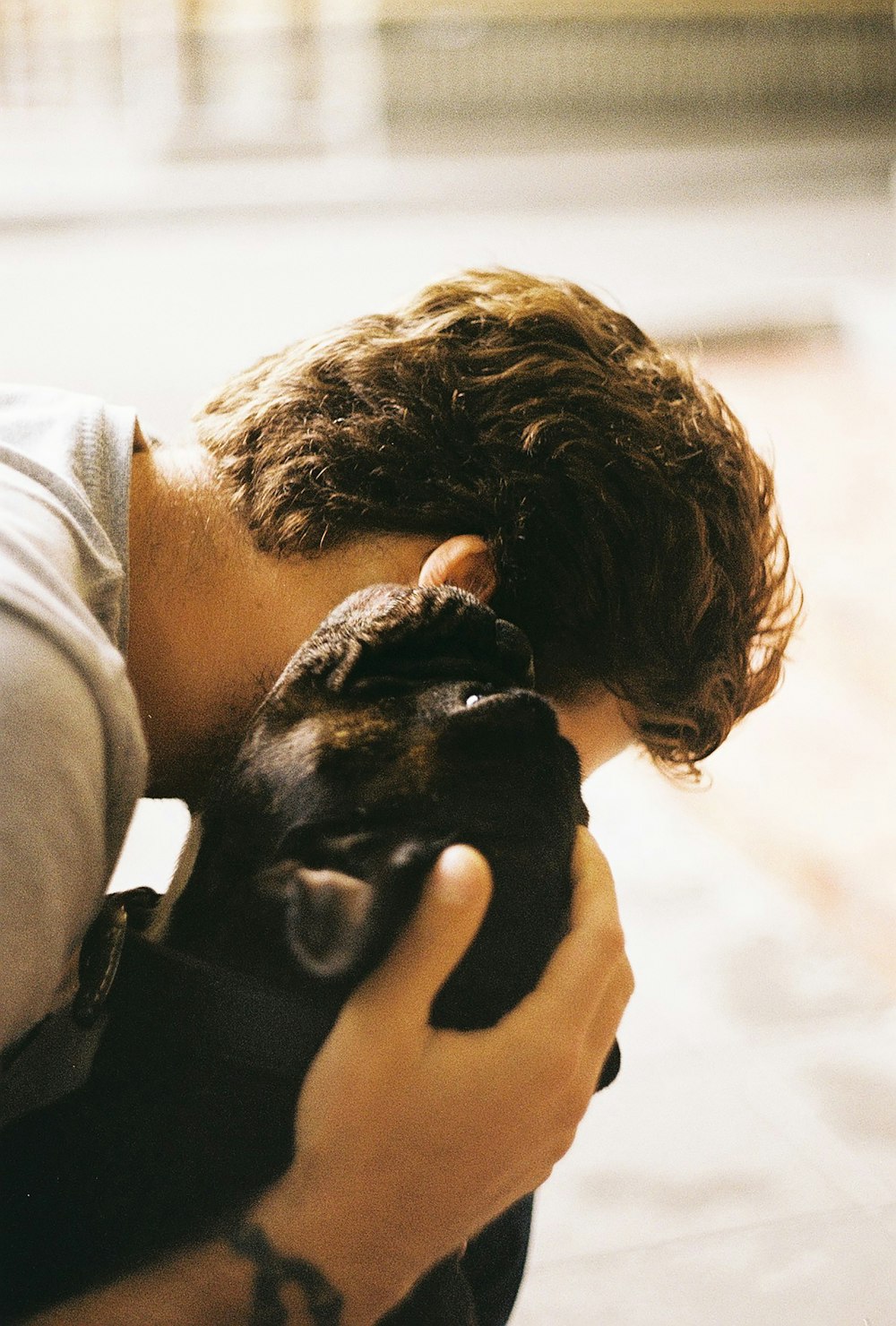 man in white hoodie carrying black short coated puppy