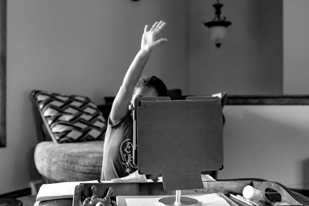 grayscale photo of woman in tank top sitting on bed