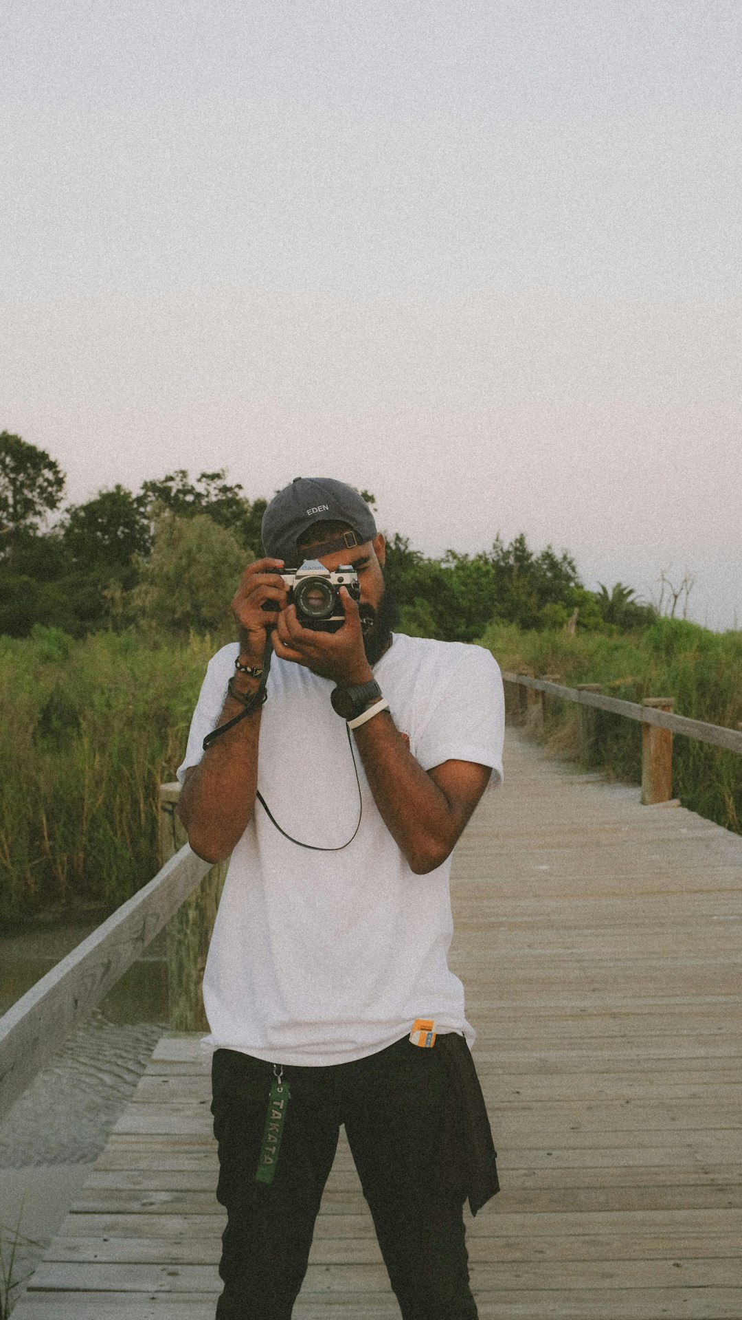 man in white t-shirt holding black dslr camera