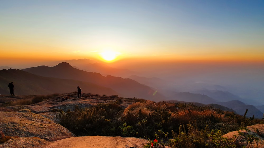 person sitting on rock during sunset