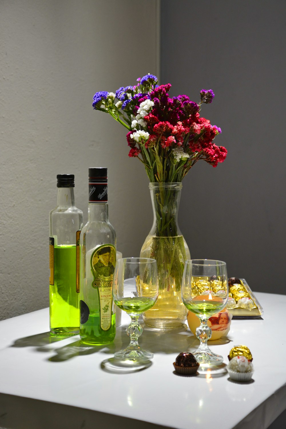 clear glass bottle with clear drinking glass and clear drinking glass on white table