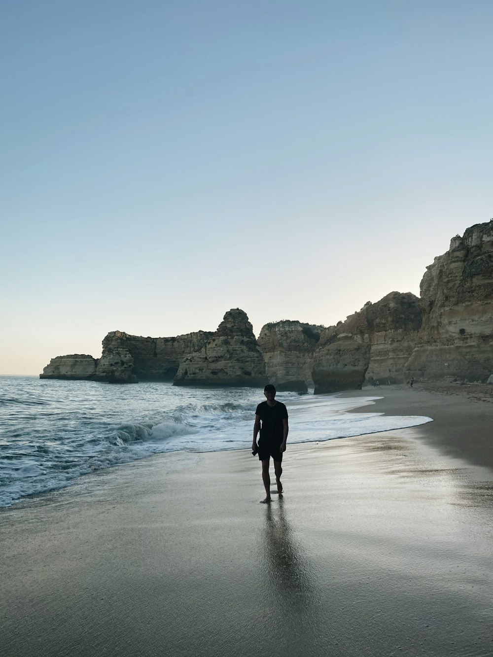 person in black jacket walking on seashore during daytime