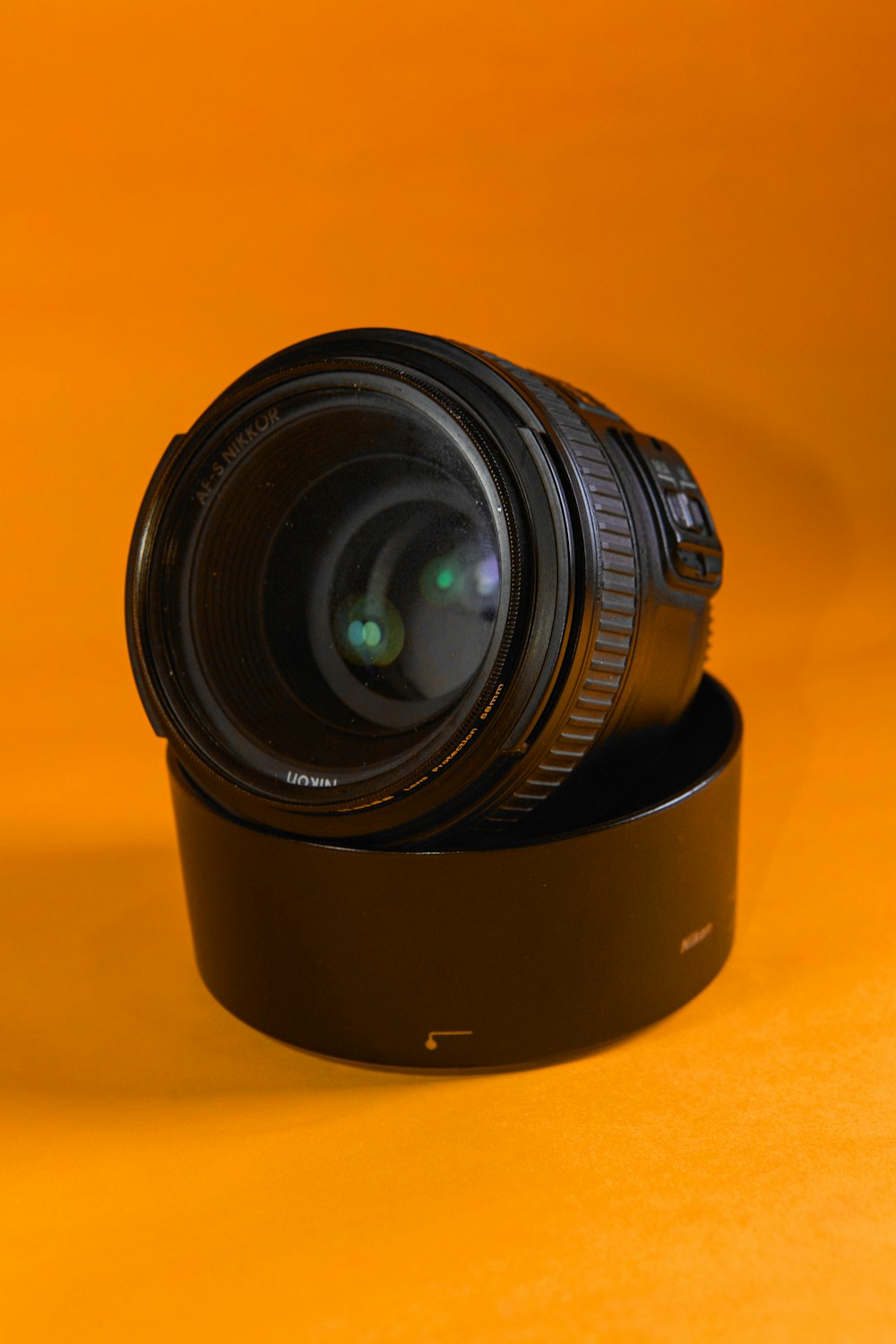 Schwarzes Kameraobjektiv auf orangefarbener Oberfläche